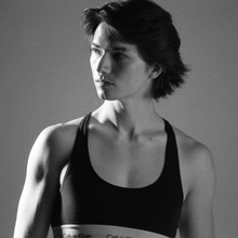 Black and white photo of figure in black sports bar in front of grey background