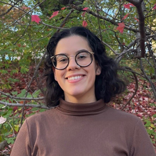 Woman with glasses in front of tree background