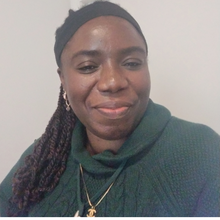 Black woman in green sweater in front of muted white background