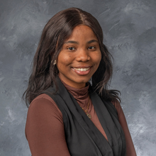 Black woman with shoulder length hair in front of grey marbled background