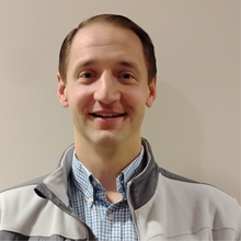 WHite man with jacket and blue shirt in front of white background