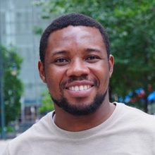 Black man smiling in front of trees