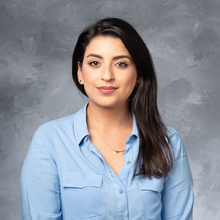 Woman in blue button down in front of grey marbled background