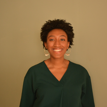 Black woman with green shirt in front of brown background