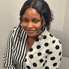 Black woman with striped/polka dot shirt in front of white background