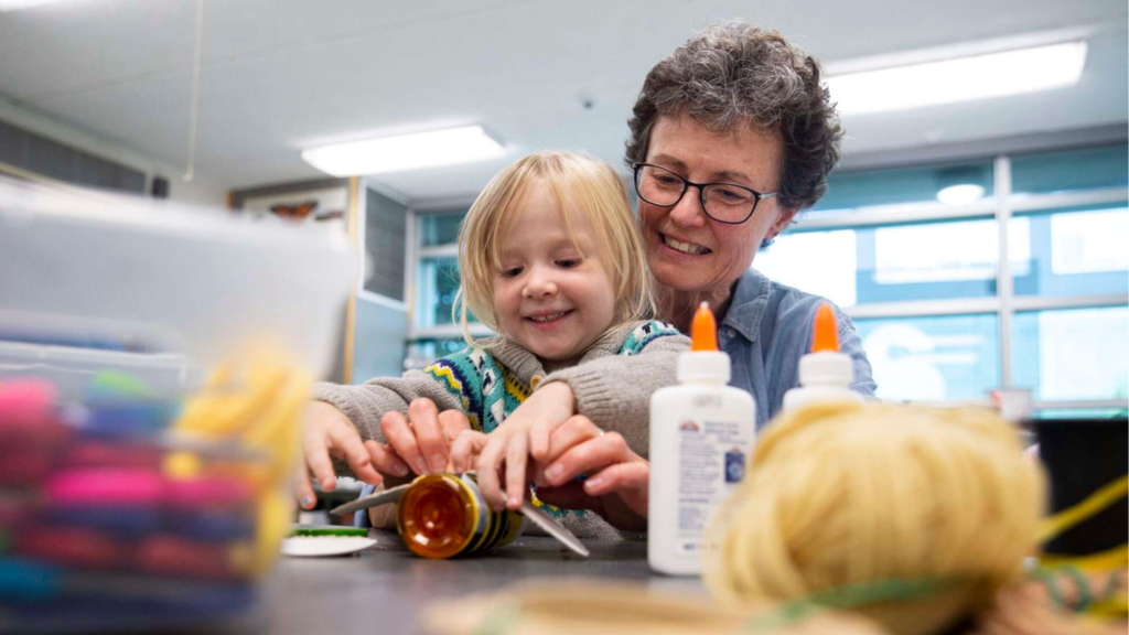 A grandmother and grandchild work on arts and crafts